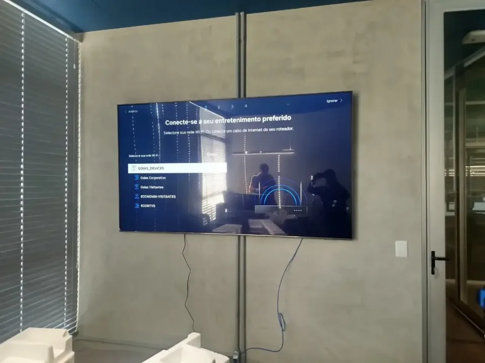 Televisão instalada na parede com cabos abaixo do aparelho