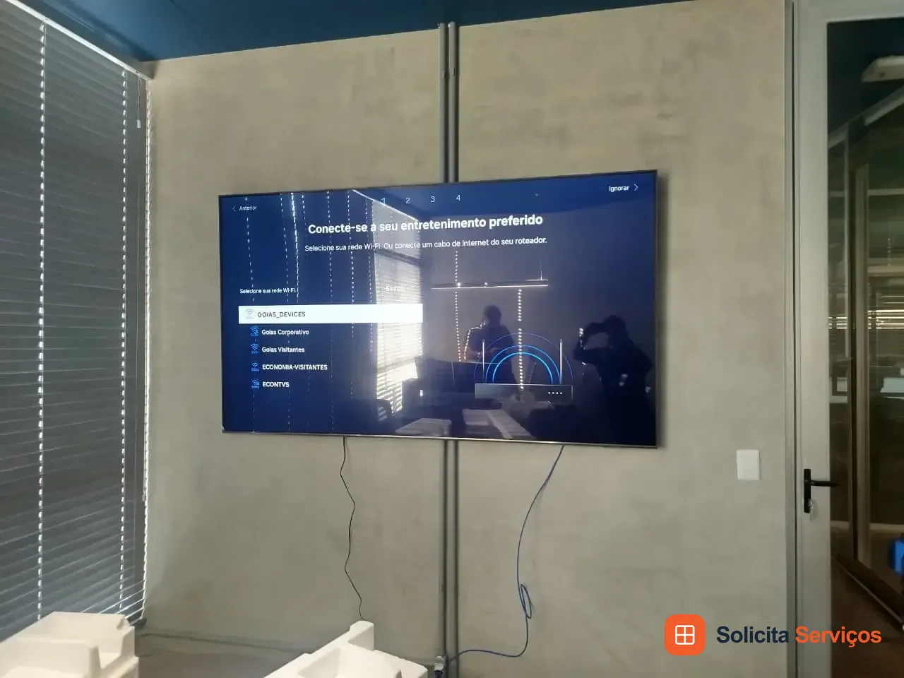 Televisão instalada na parede com cabos abaixo do aparelho