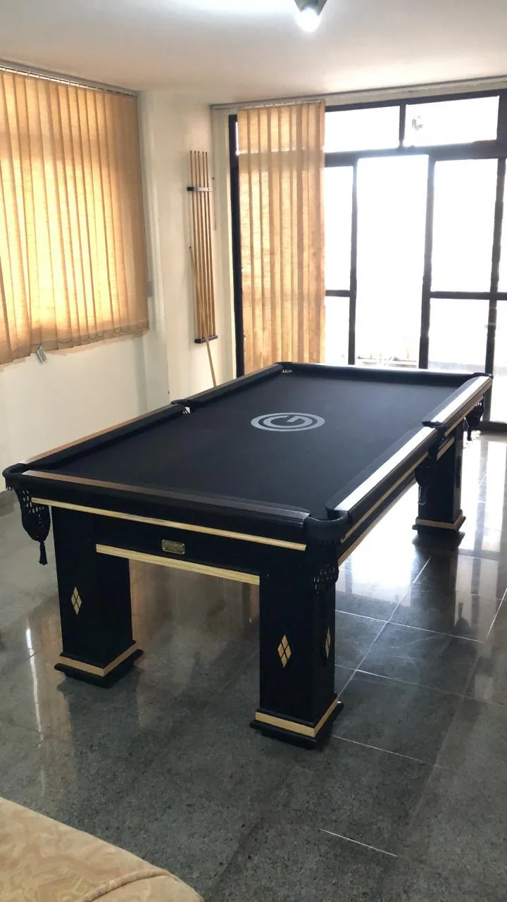 Mesa de bilhar com tecido escuro em ambiente interno