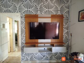 Painel ripado com televisão e móvel de apoio claro, no acervo do profissional.