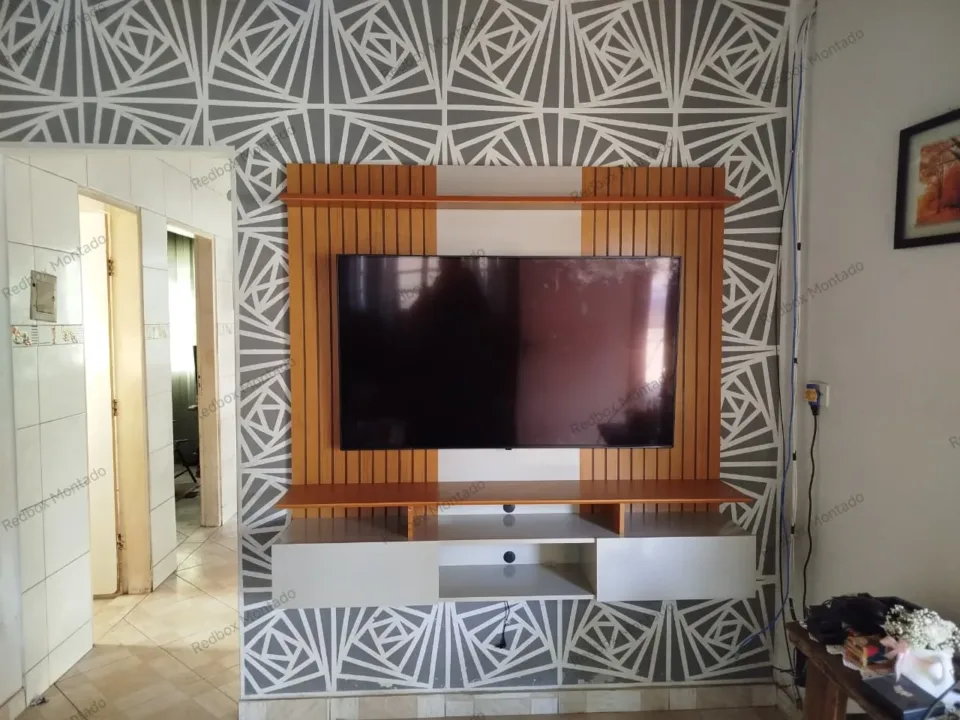 Painel ripado com televisão e móvel de apoio claro.