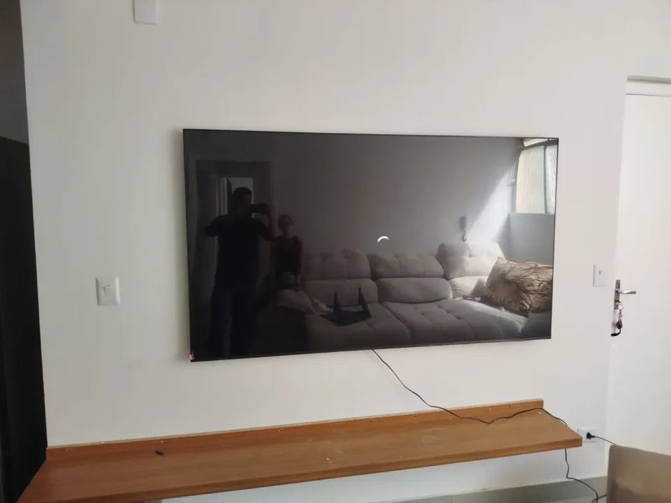 TV fixada na parede acima de um móvel de apoio.