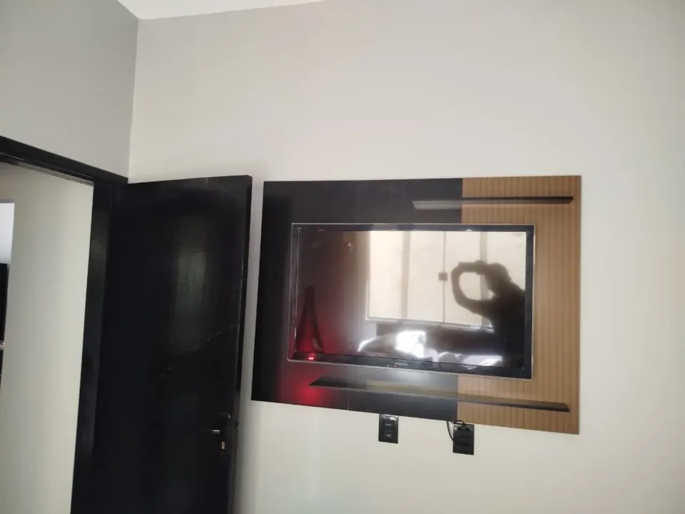 Fotografia do acervo com painel de duas cores e televisão posicionada à frente.