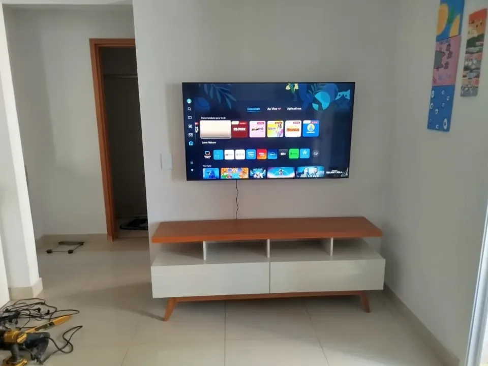 Fotografia do acervo com rack claro e tampo em acabamento amadeirado.